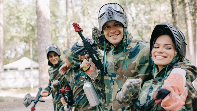 Cute couple smiling and enjoying a game of paintball dressed in camoflauge.